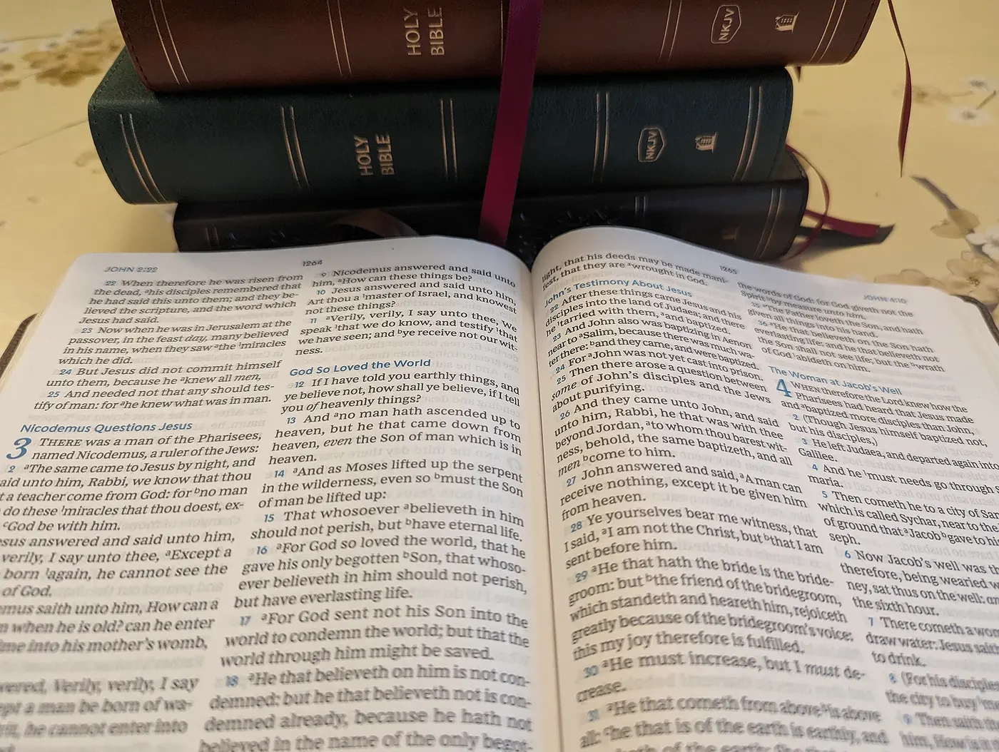 An open Bible in front of a stack of Bibles