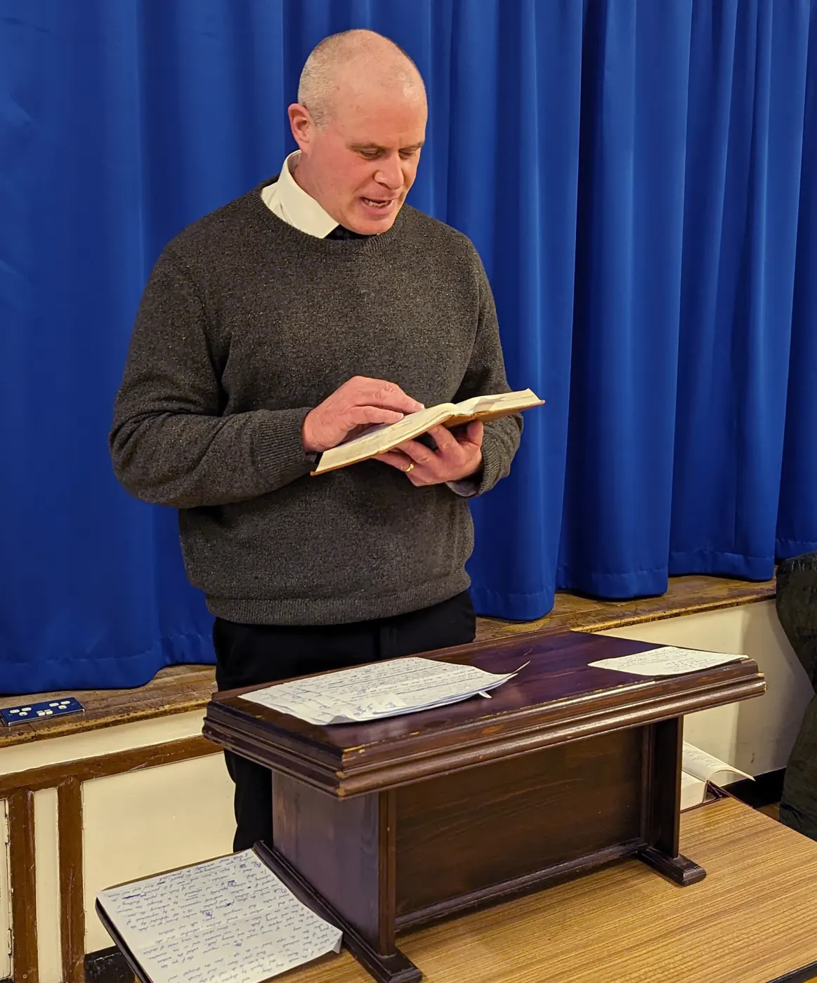 Pastor Matthew Richer reading from the Bible at the lectern